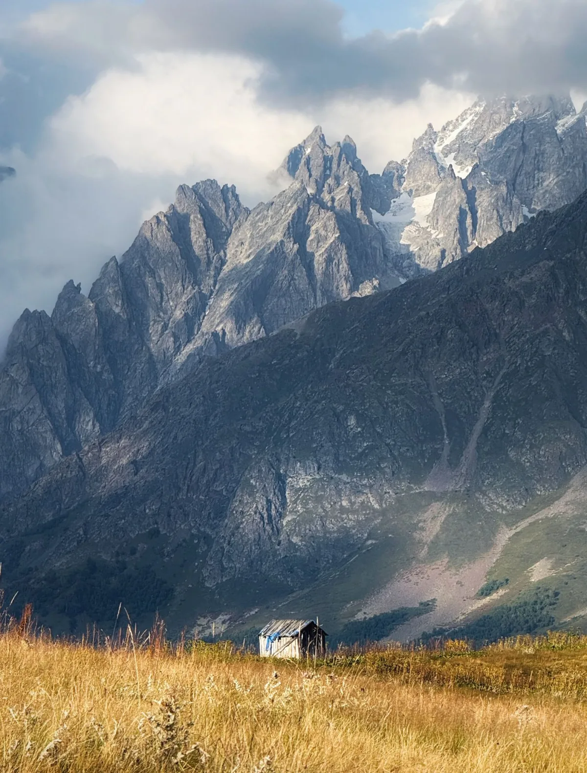 A hut in the long grass under the peaks of Svaneti